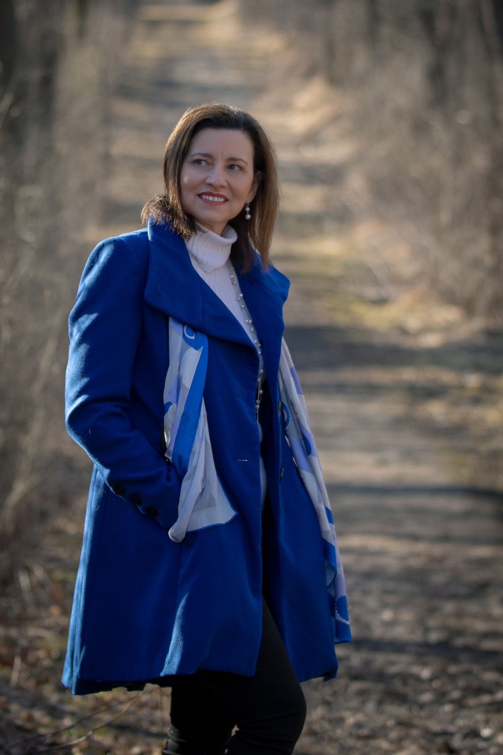 Woman in a blue coat in a wooded setting