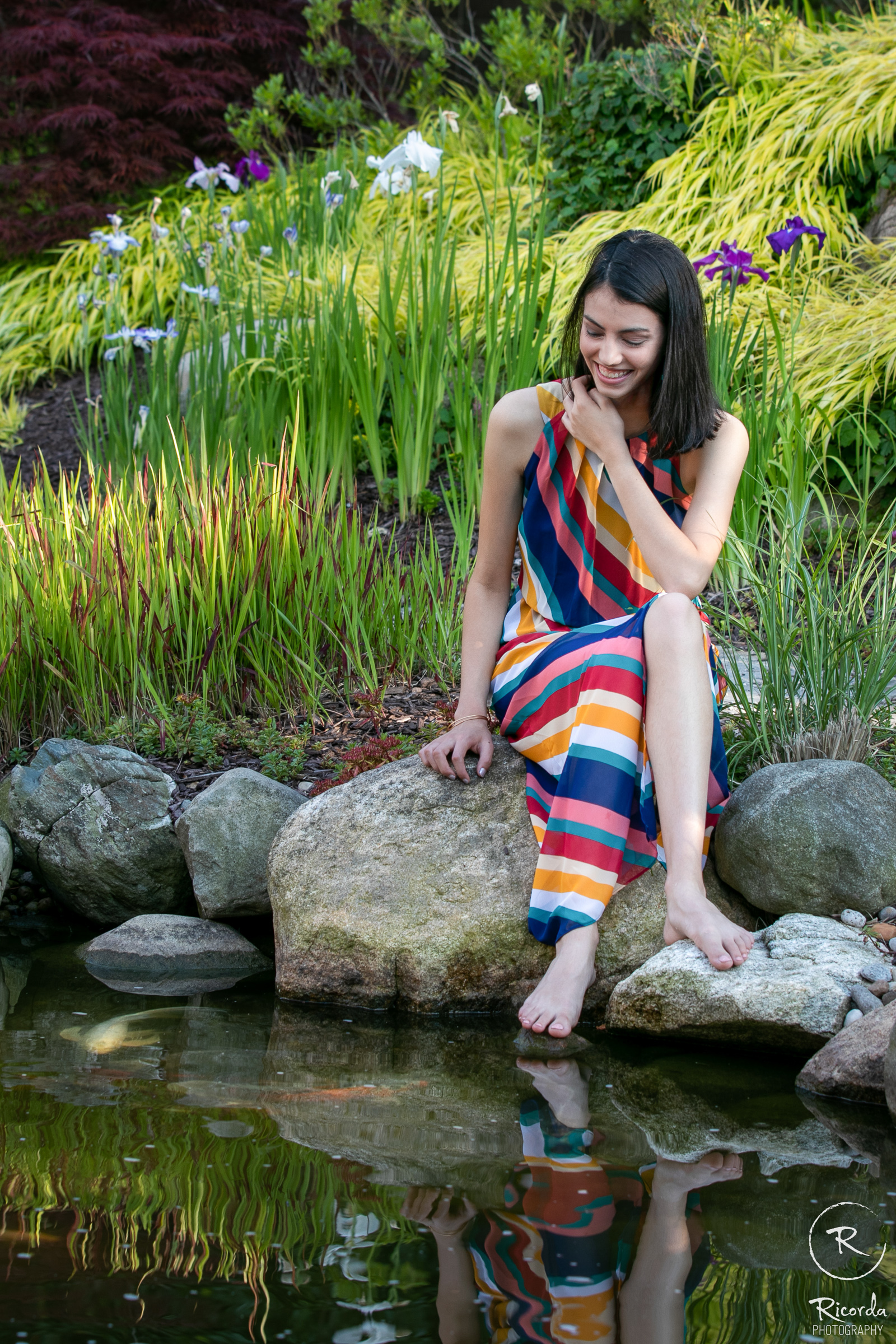 Portrait in a striped dress by a garden pond