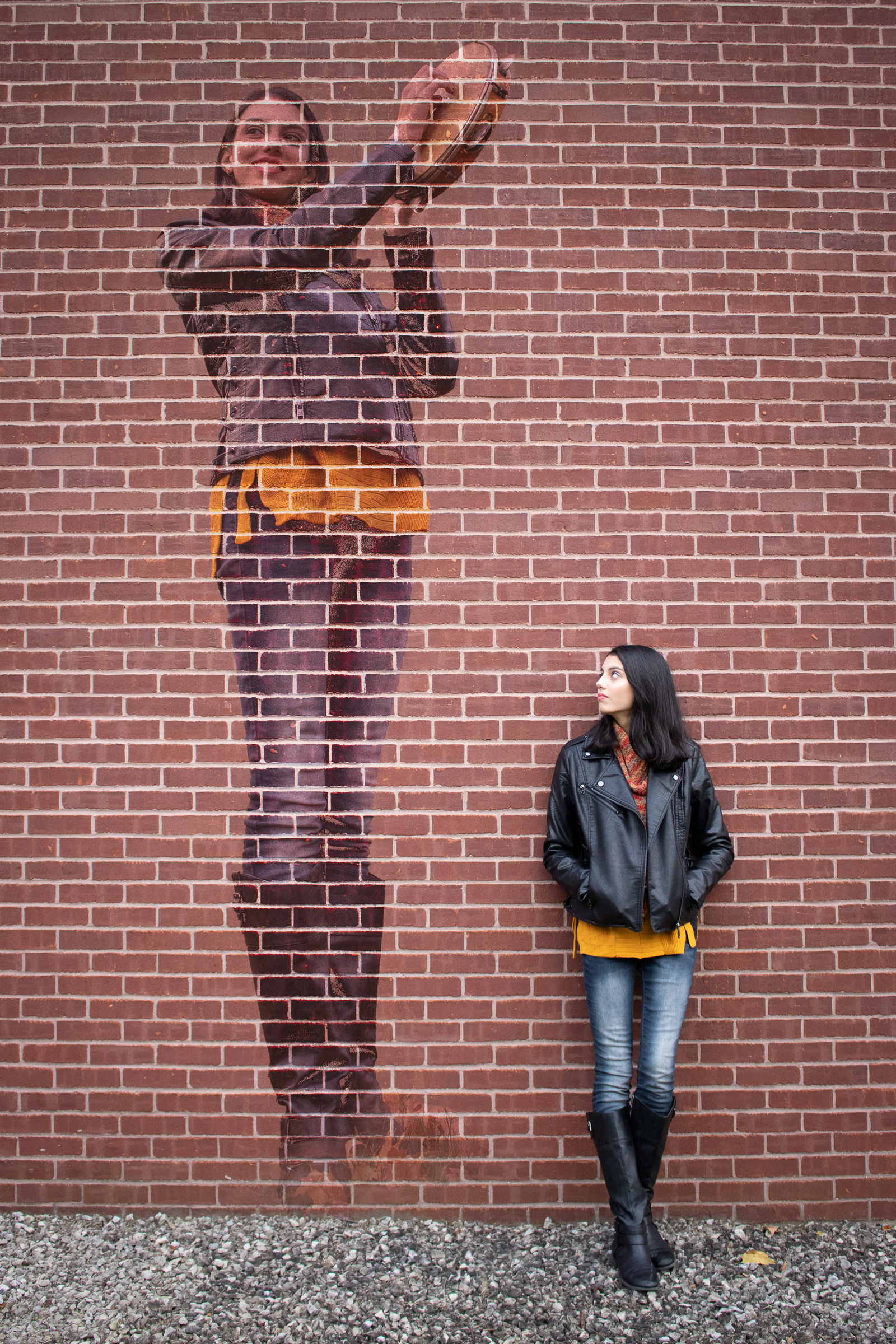 Portrait beside a large painted mural on a brick wall