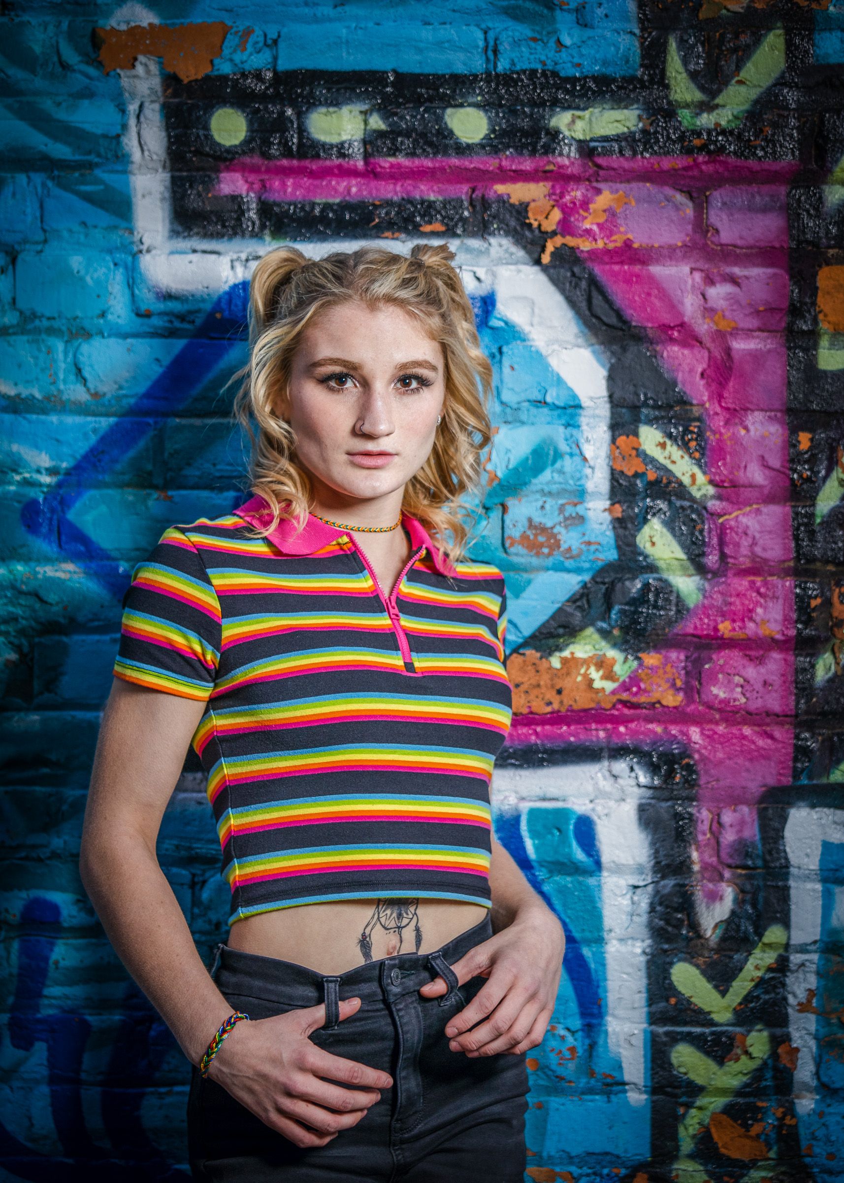 Senior in a striped top in front of a colorful mural