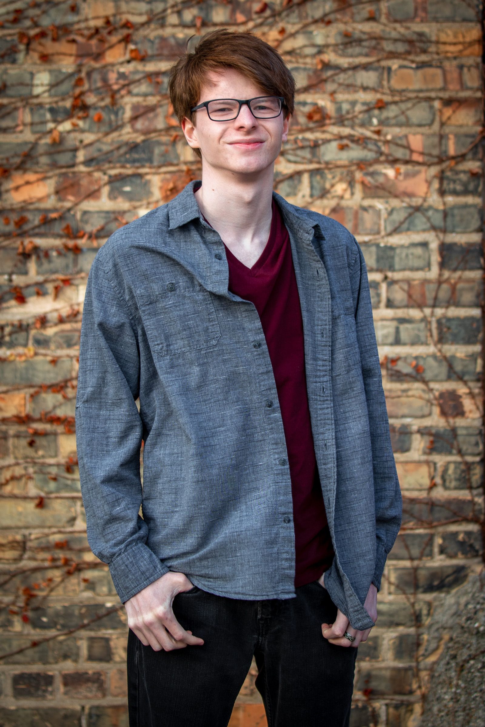 Senior guy in a denim shirt against brick
